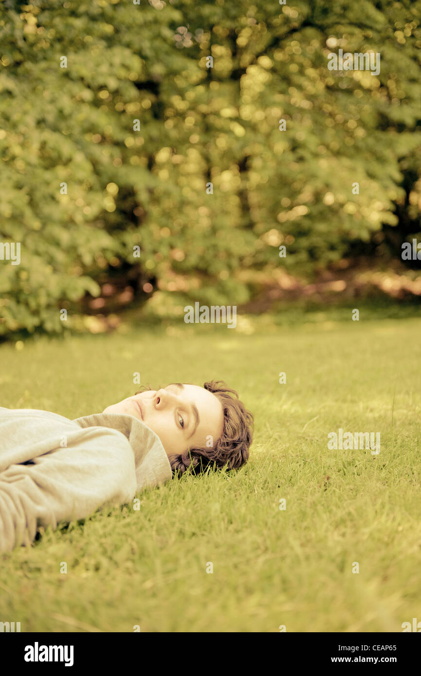 Junge Mann liegt auf dem Rasen, Blick in die Kamera Stockfoto