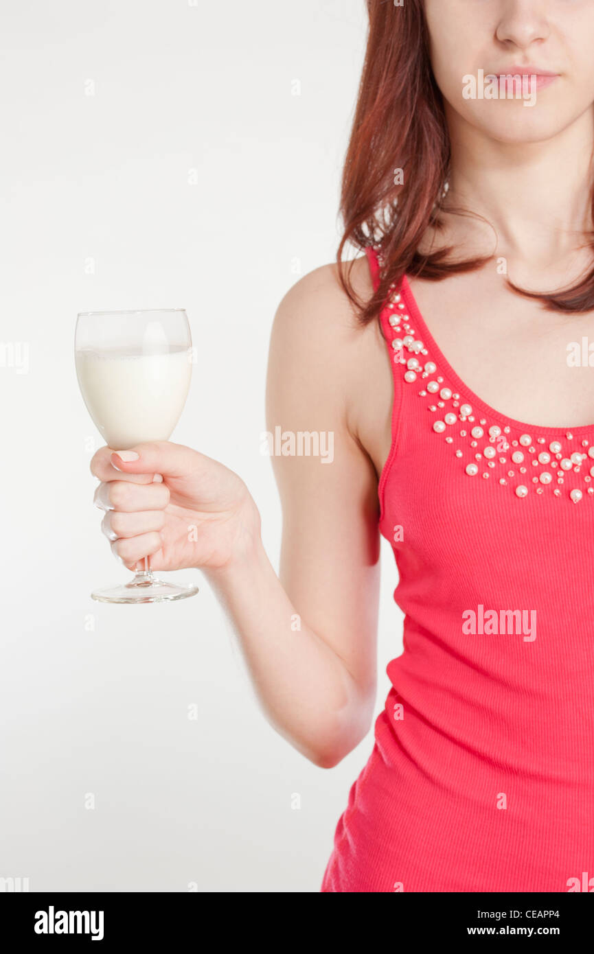 Junge Frau im roten Kleid hält ein Weinglas mit Milch Stockfoto