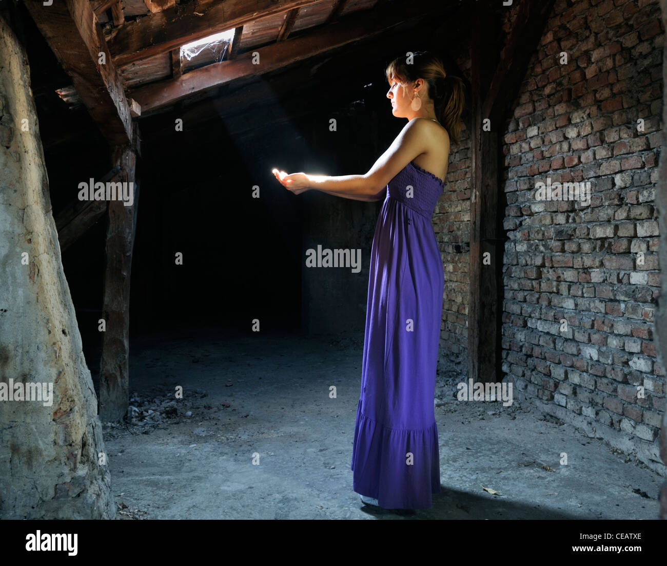 Junge Frau im Dachboden Licht zwischen den Händen einzufangen Stockfoto