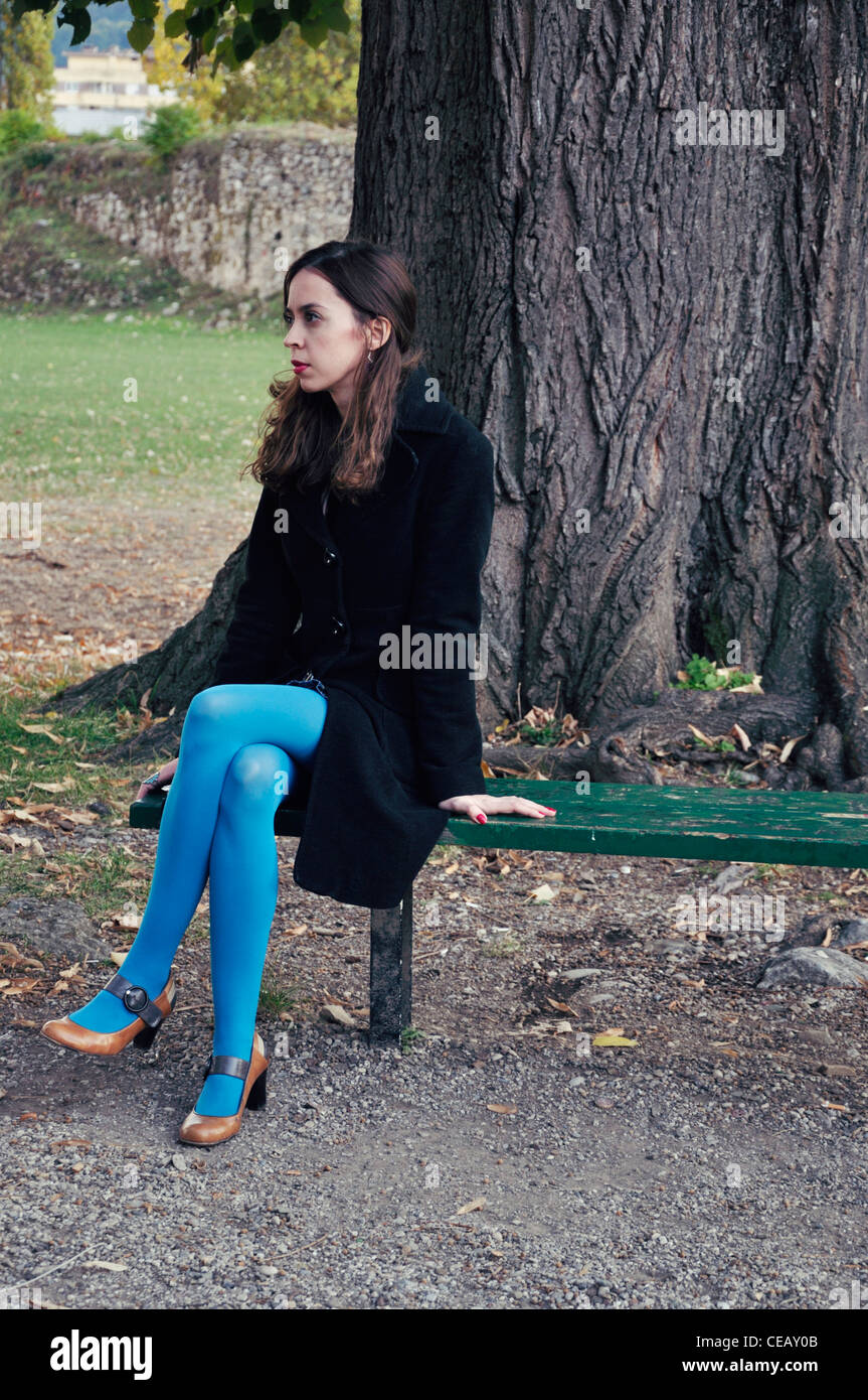 Junge Frau allein auf Park Bank im Freien sitzen Stockfoto