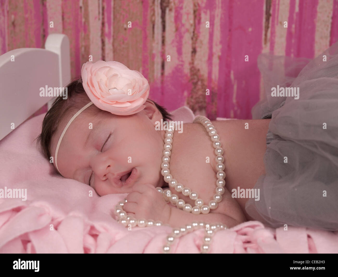 Closeup ein wunderschönes neugeborenes Mädchen mit rosa geblümten Stirnband, grau Tutu und Perlen, ist sie eingeschlafen. Stockfoto