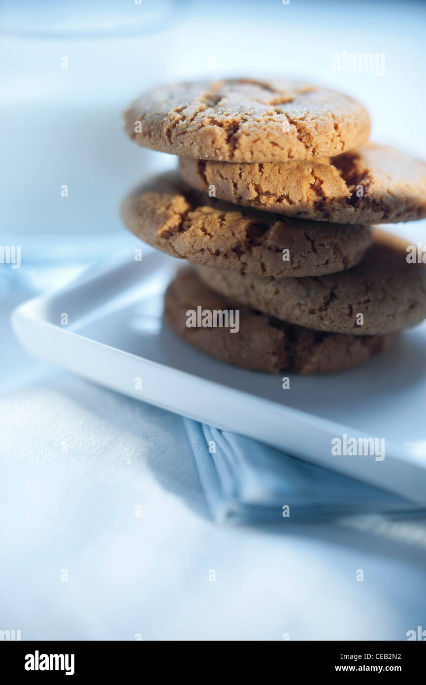 Ginger Snap Cookies (Kekse) mit einem Glas Milch auf weißem Geschirr serviert. Stockfoto