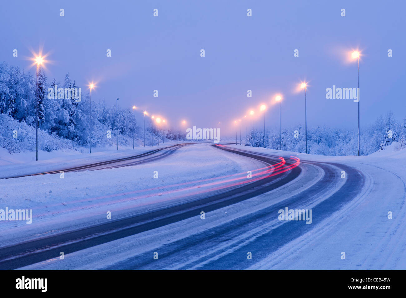 Langsame Verschlusszeit fängt Bremslichter der Autos als eine Unschärfe an einem kalten, nebligen Wintermorgen in der Nähe von Eagle River, Alaska. Stockfoto
