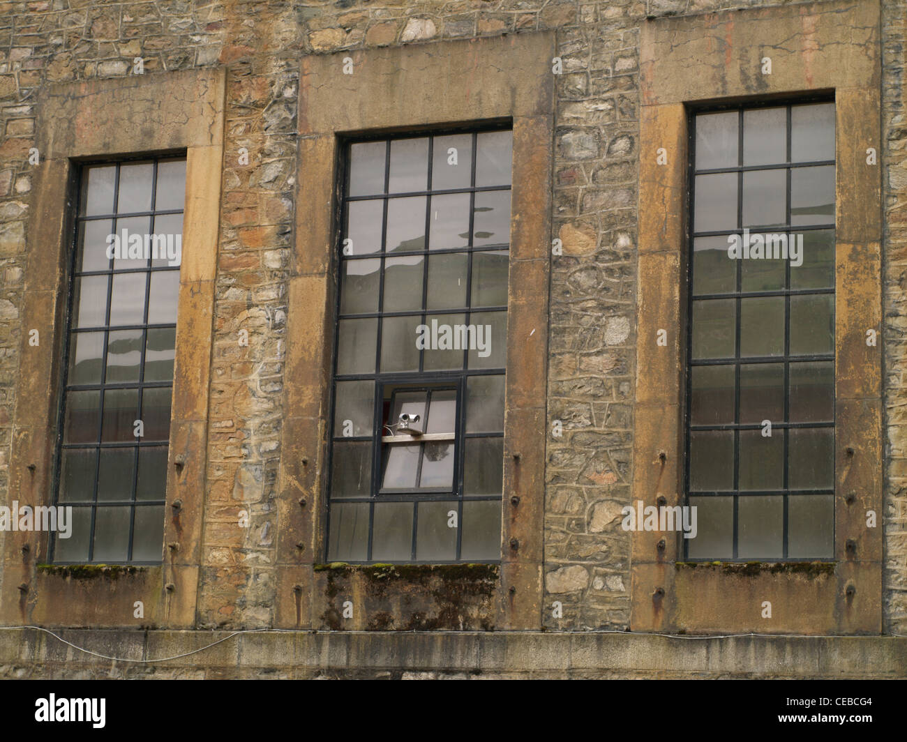 Eine CCTV-Kamera an der Seite einer Fabrik mit Steinmauern und industrielle Windows gemacht Stockfoto
