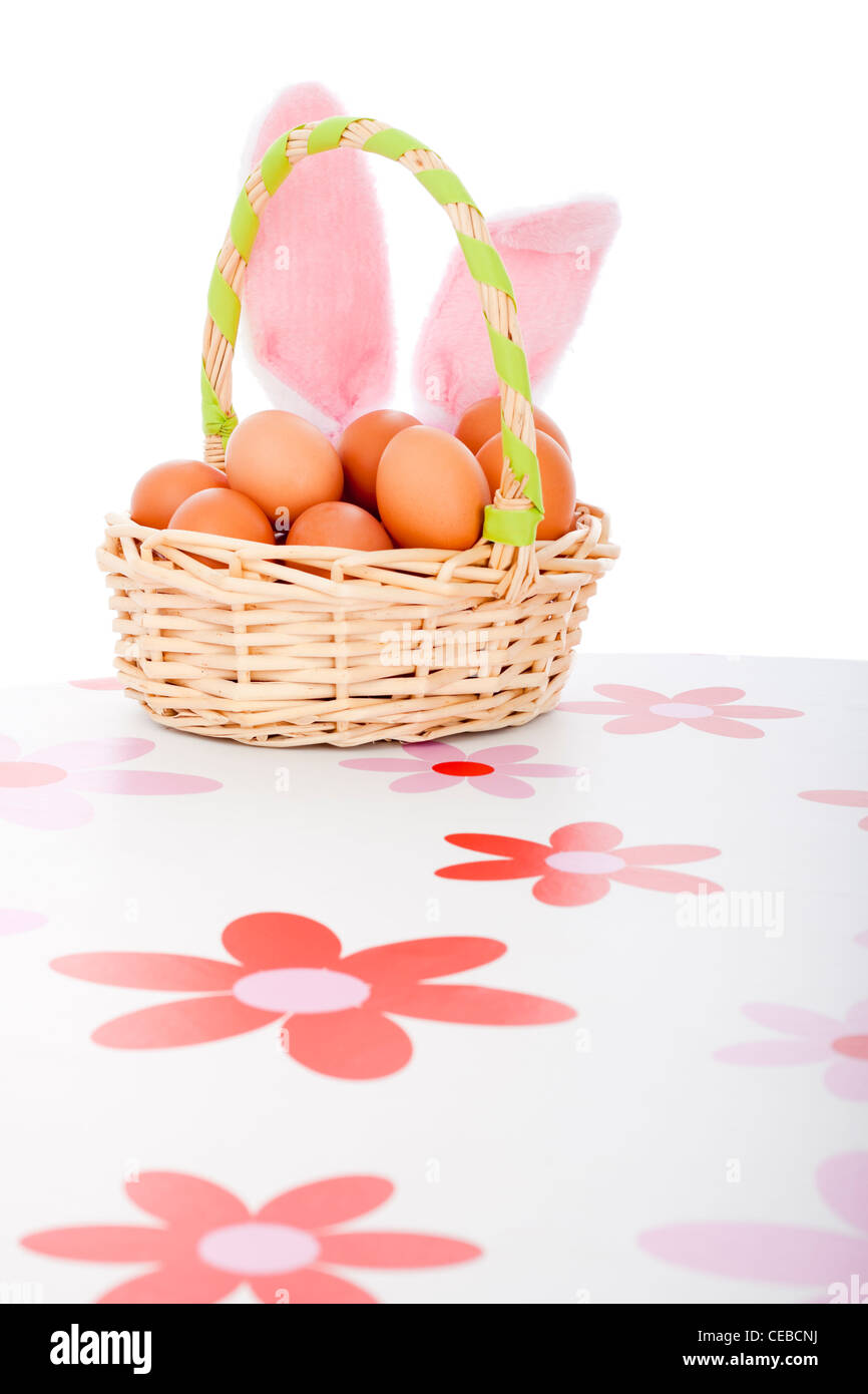 Osterkorb mit Eiern und Hasenohren, isoliert auf weißem Hintergrund. Stockfoto