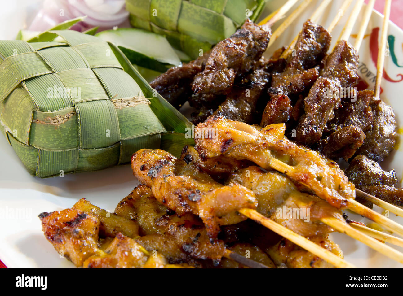 Huhn und Lamm Satay Spieße mit Ketupat Reis in Kokos-Blatt gewickelt Stockfoto