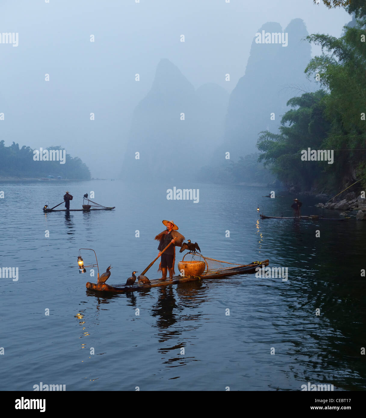 Kormoran Fischer in Nebel im Morgengrauen auf dem Li-fluss mit karst Berggipfel in der Nähe von xingping China Stockfoto