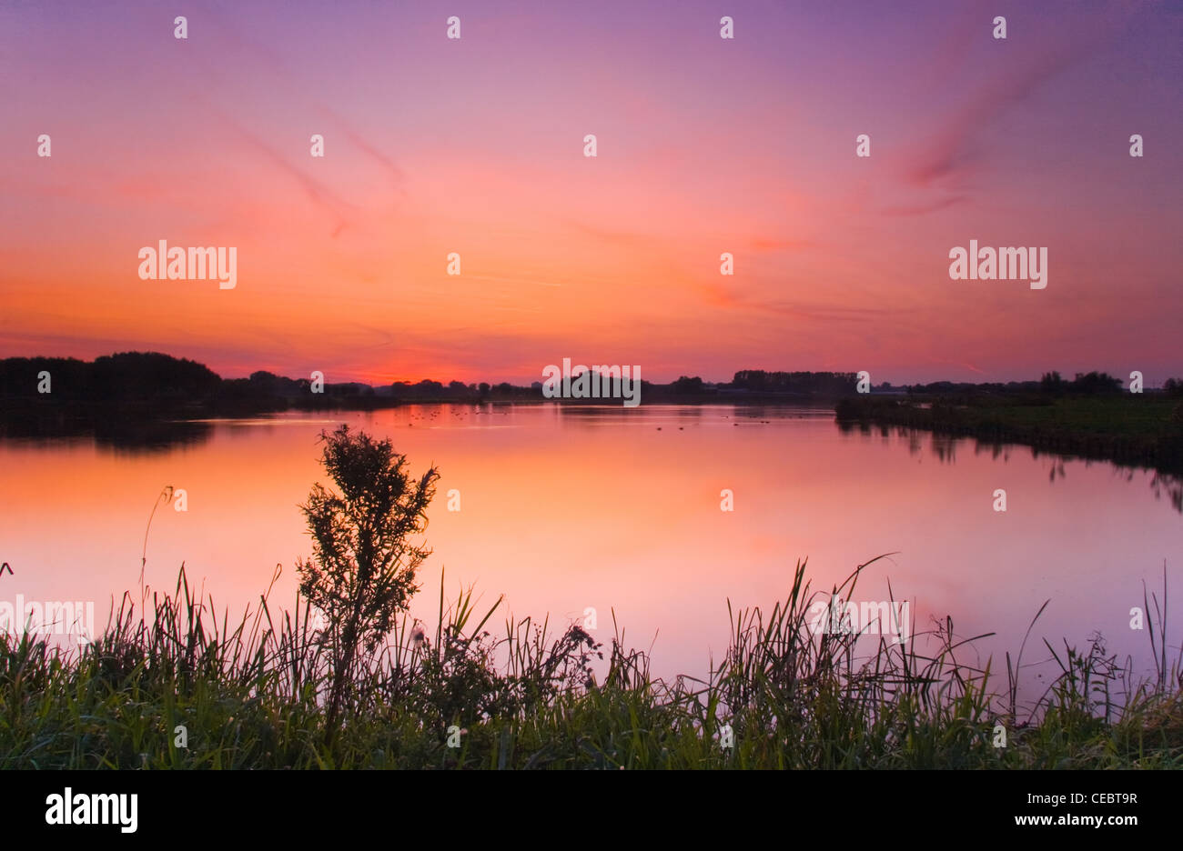 Extrem farbenprächtigen Sonnenuntergang am See in blau, Orange und pink Stockfoto
