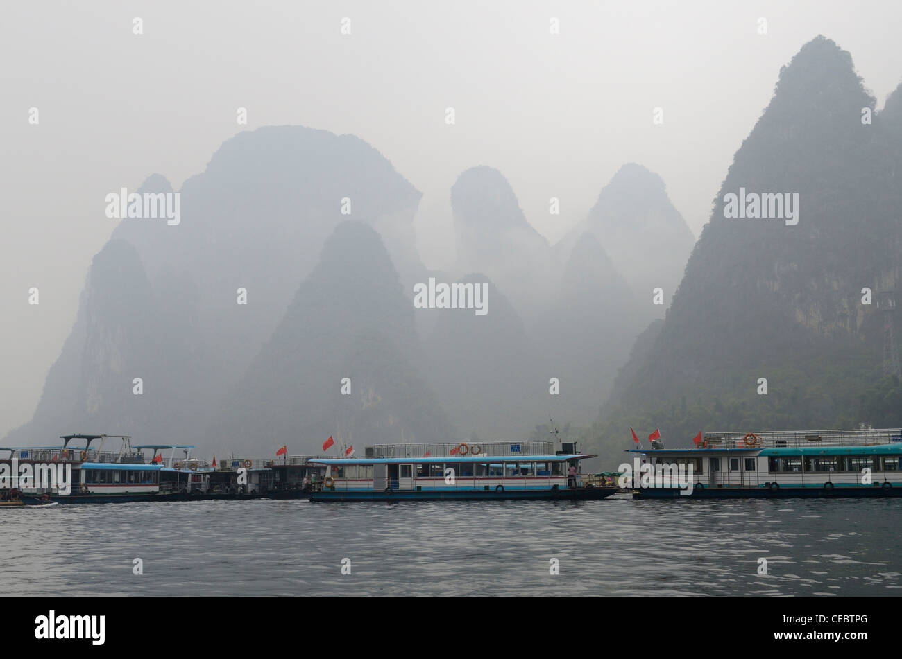 Ausflugsboot Lastkähne auf dem Li-Fluss bei Xingping mit Karst Kalkstein Gipfel im Nebel Peoples Republic Of China Stockfoto