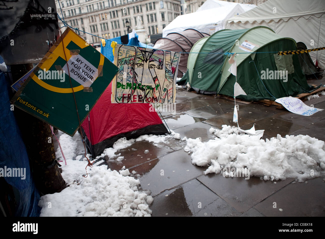 Banner und Zelte in St. Pauls Besetzung Camp. Ein Schild steht "Mein Zelt für Ihren Bonus" mit Zelten und Schnee hinter. Stockfoto