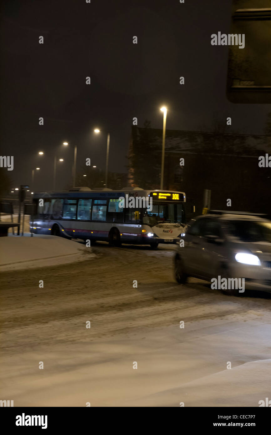 Bus mit Licht fahren um einen Kreisverkehr bei winterlichen/Schnee Wetter bei Nacht Stockfoto