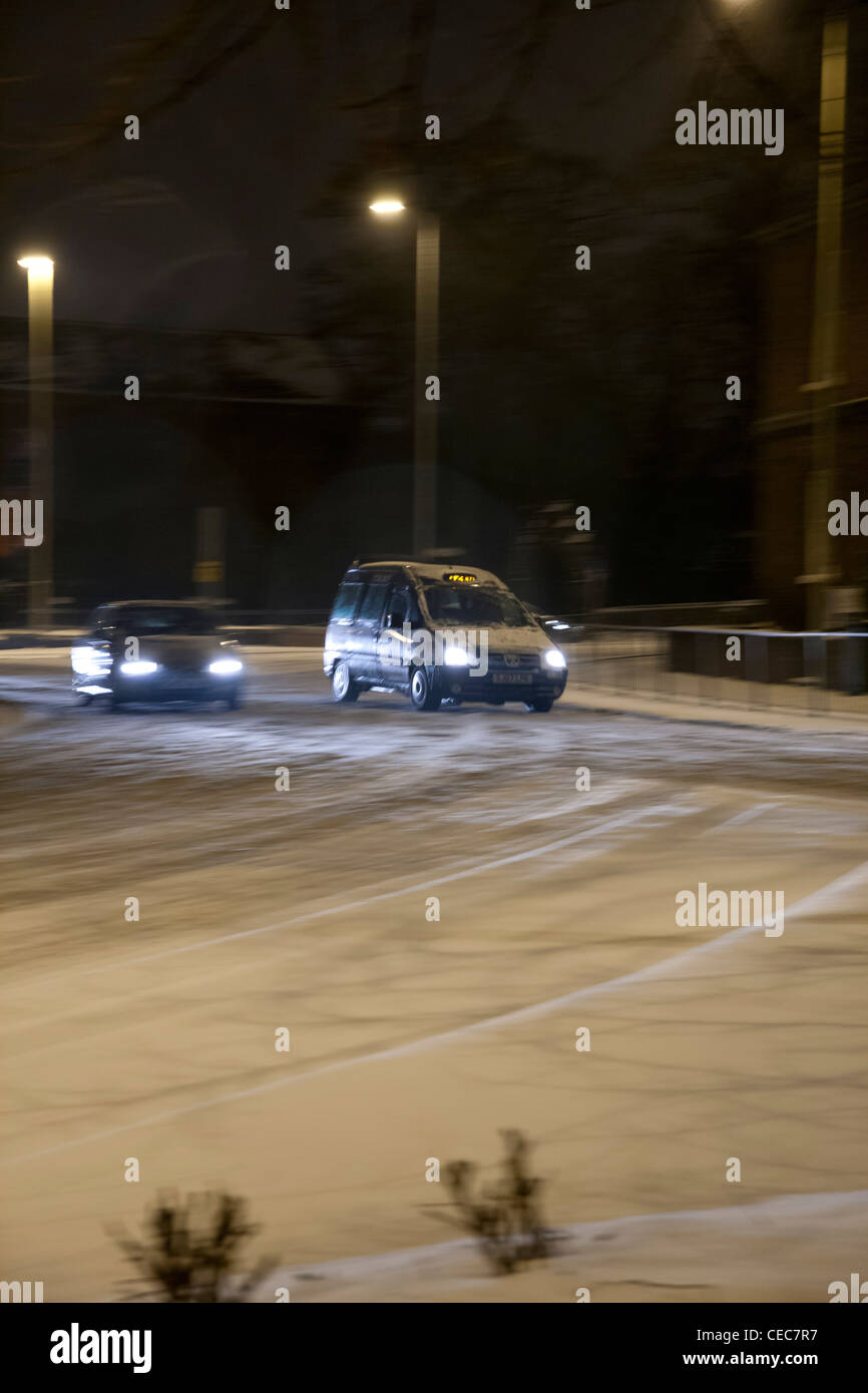 Auto mit Licht fahren um einen Kreisverkehr bei winterlichen/Schnee Wetter bei Nacht Stockfoto