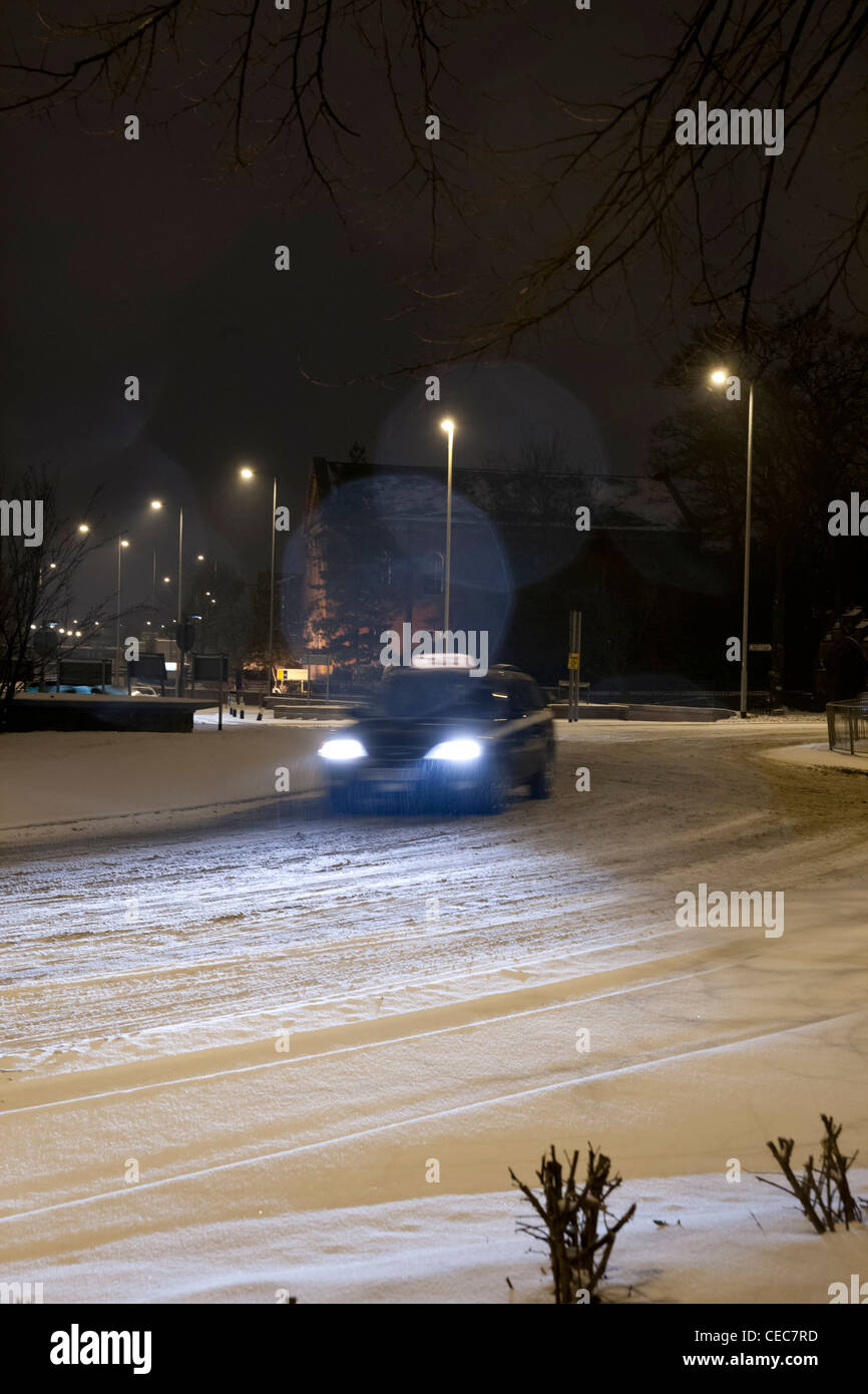 Taxi in der Nacht um einen Kreisverkehr fahren im Schnee Stockfoto