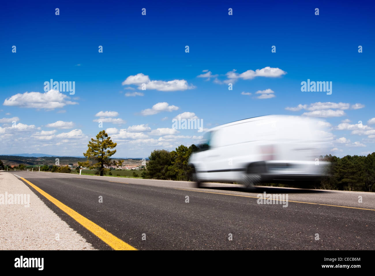 Weiße van in einem Land unterwegs mit einigen Bäumen und einem großen blauen Himmel oben Stockfoto