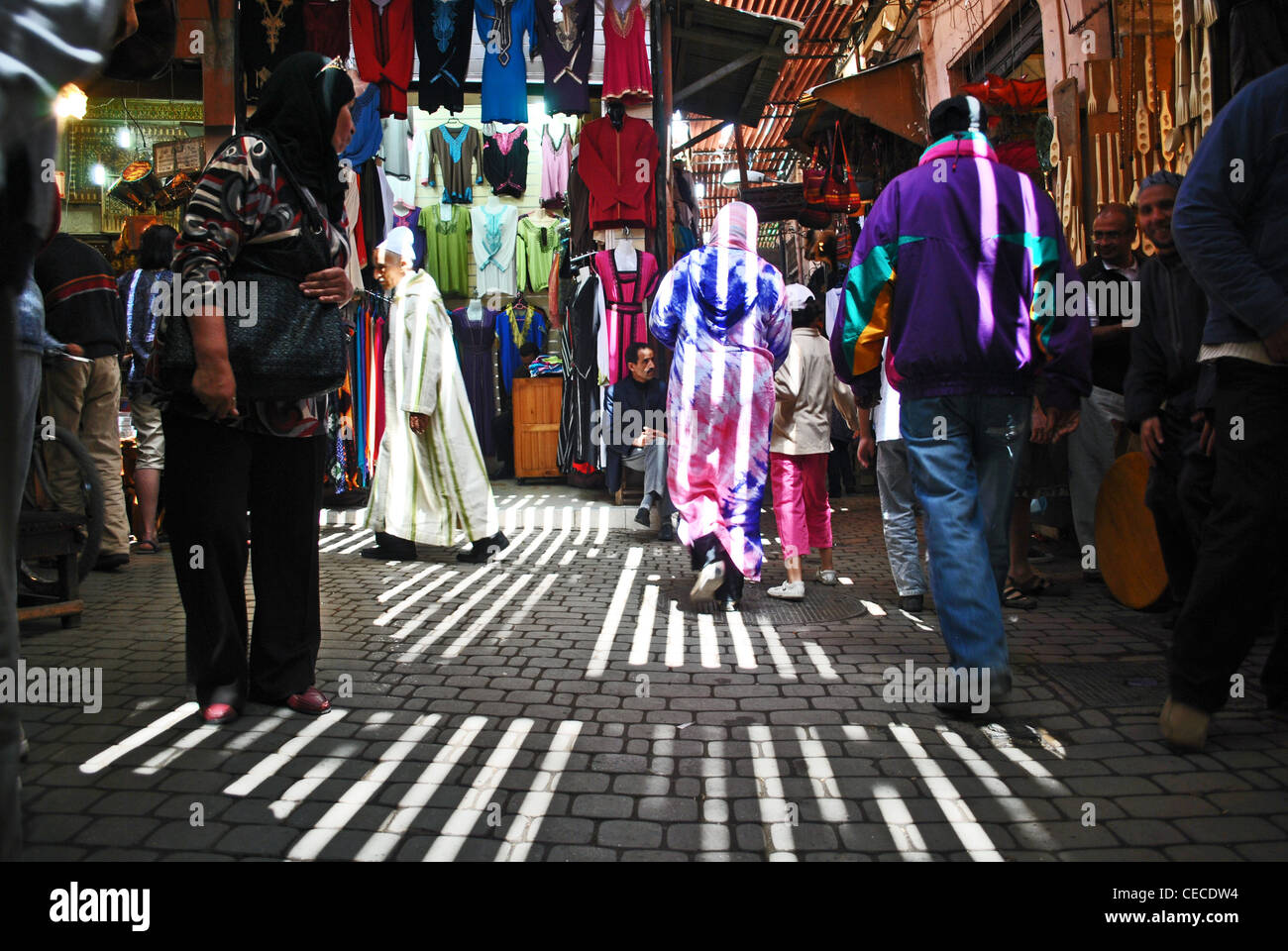 Die Menschen gehen über einen belebten Souk in Marrakesch, Marokko, als Licht strömt durch Lamellen in der Decke Stockfoto