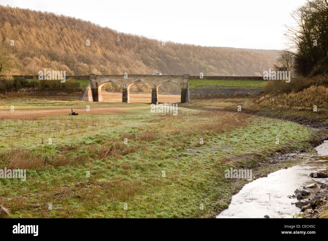 Stream läuft über ausgetrockneten Bett des Lindley Holz Behälter (niedriger Wasserstand nach trockenen Herbst) & 3-arch Road Bridge - North Yorkshire, England, UK. Stockfoto