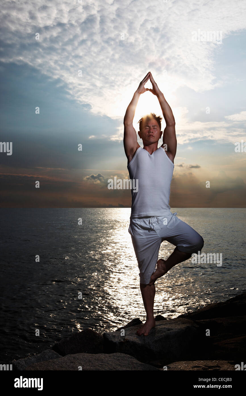 Hintergrundbeleuchtung Schuss der Mann tut Yoga in der Nähe von Wasser Stockfoto