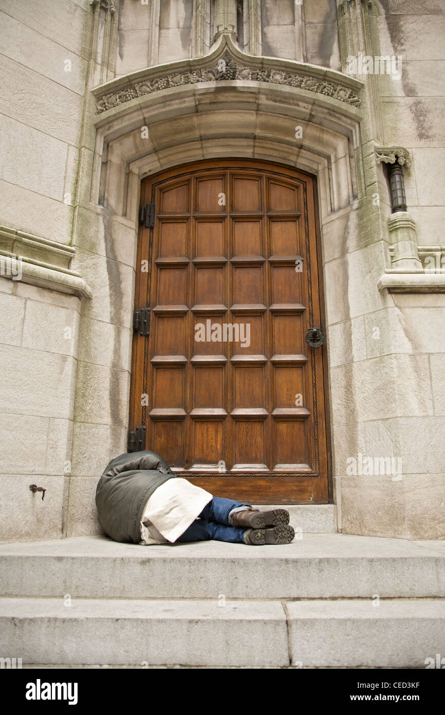 Obdachloser schlafen gegen Seitentür St. Thomas Church 5th Avenue in New York City. Stockfoto