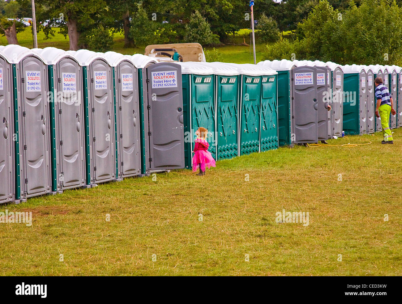 junges Mädchen in rosa Fee Kostüm warten auf Toilette auf einem Festival zu benutzen Stockfoto