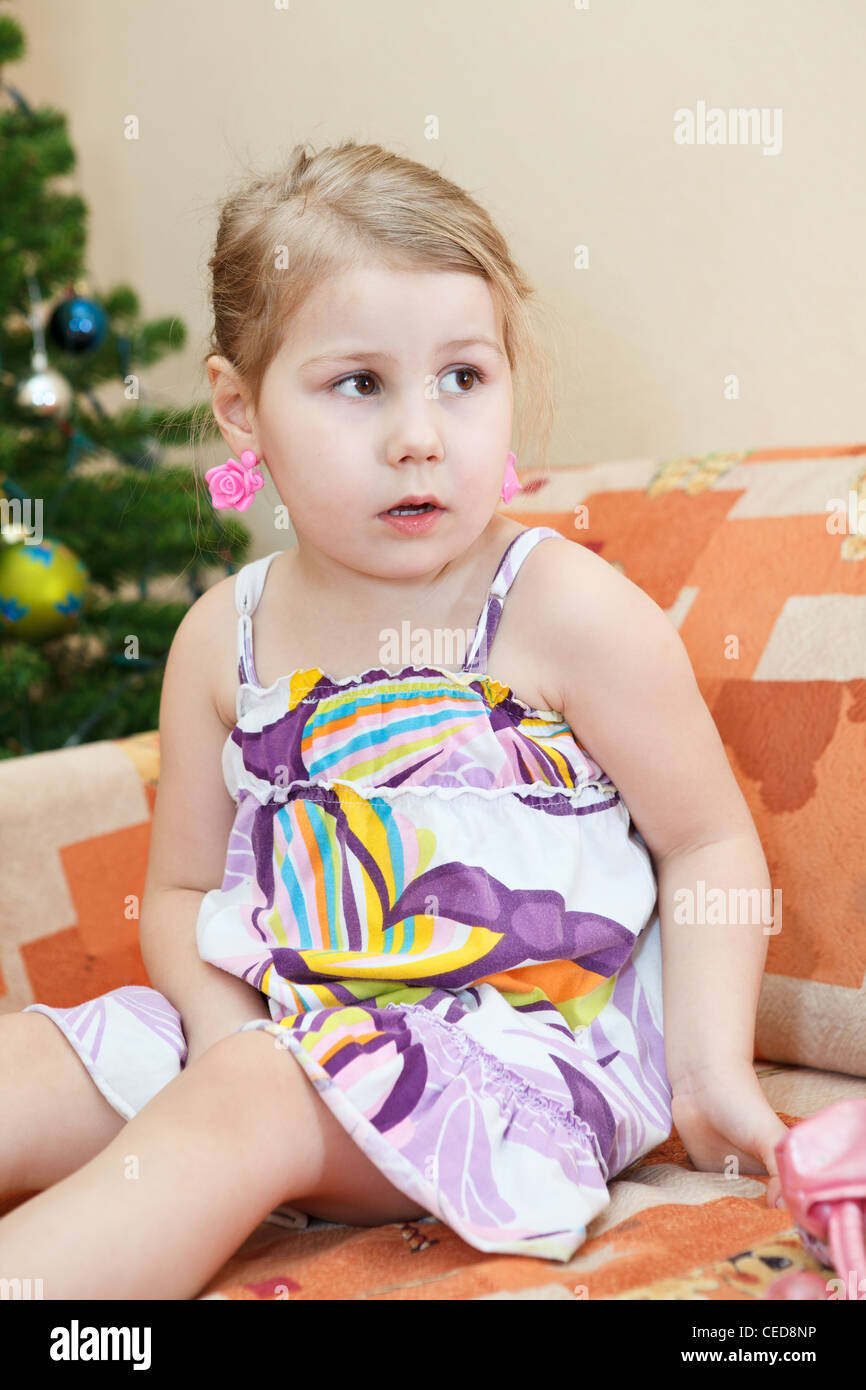 Kleine russische lächelndes Mädchen sitzen auf der Couch hinter Weihnachtsbaum im Wohnraum Stockfoto
