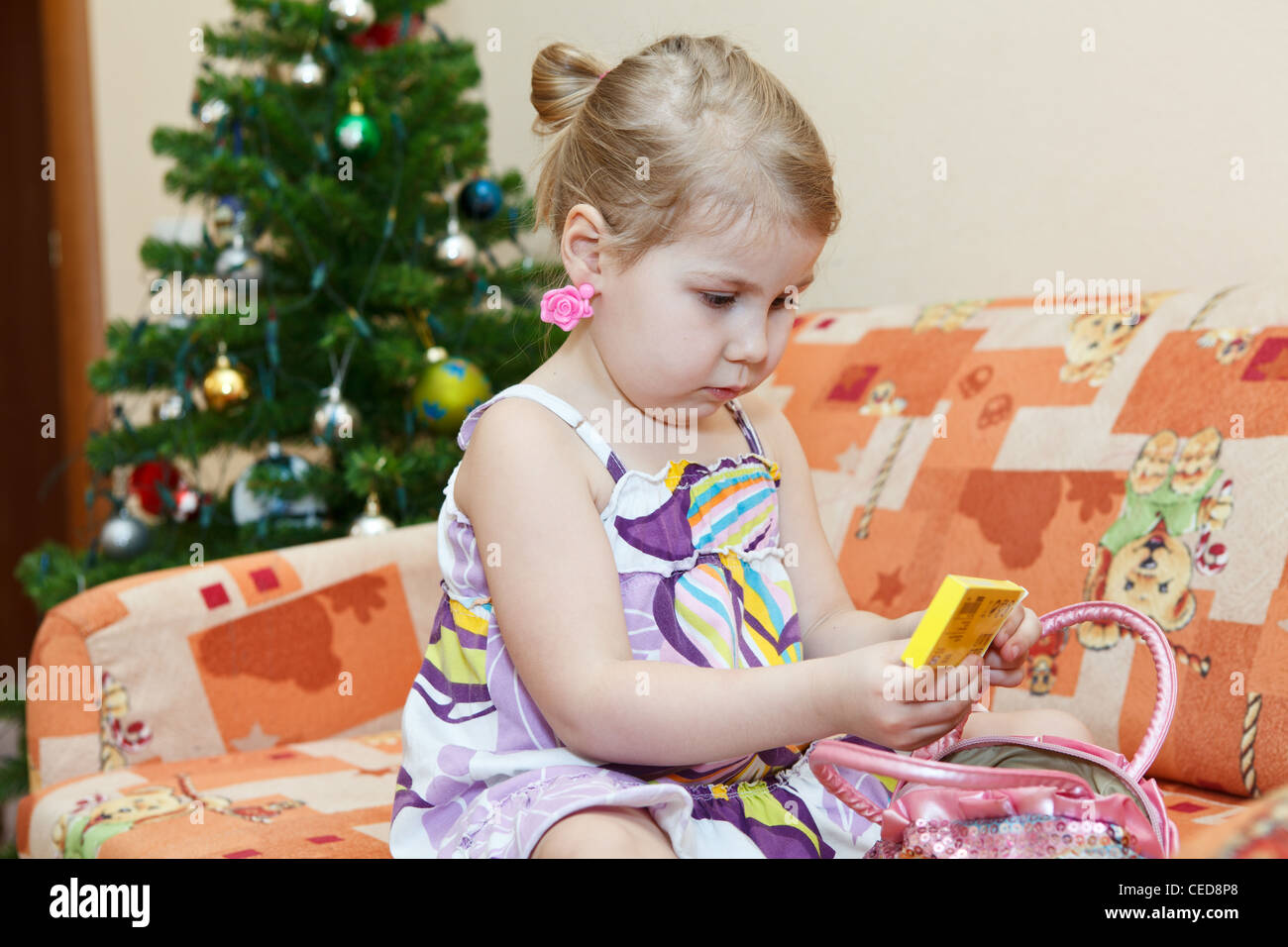 Kleine russische lächelndes Mädchen sitzen auf der Couch hinter Weihnachtsbaum im Wohnraum Stockfoto