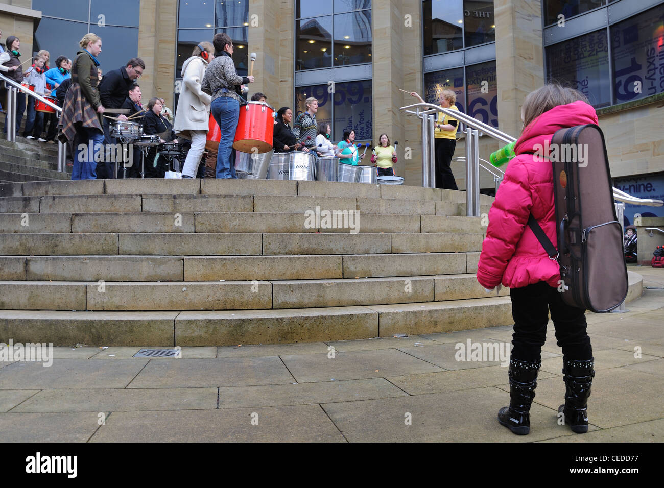 Ein kleines Mädchen Uhren die Celtic Connections Samba Trommler auf die Schritte der Royal Concert Hall in Glasgow, Schottland Stockfoto