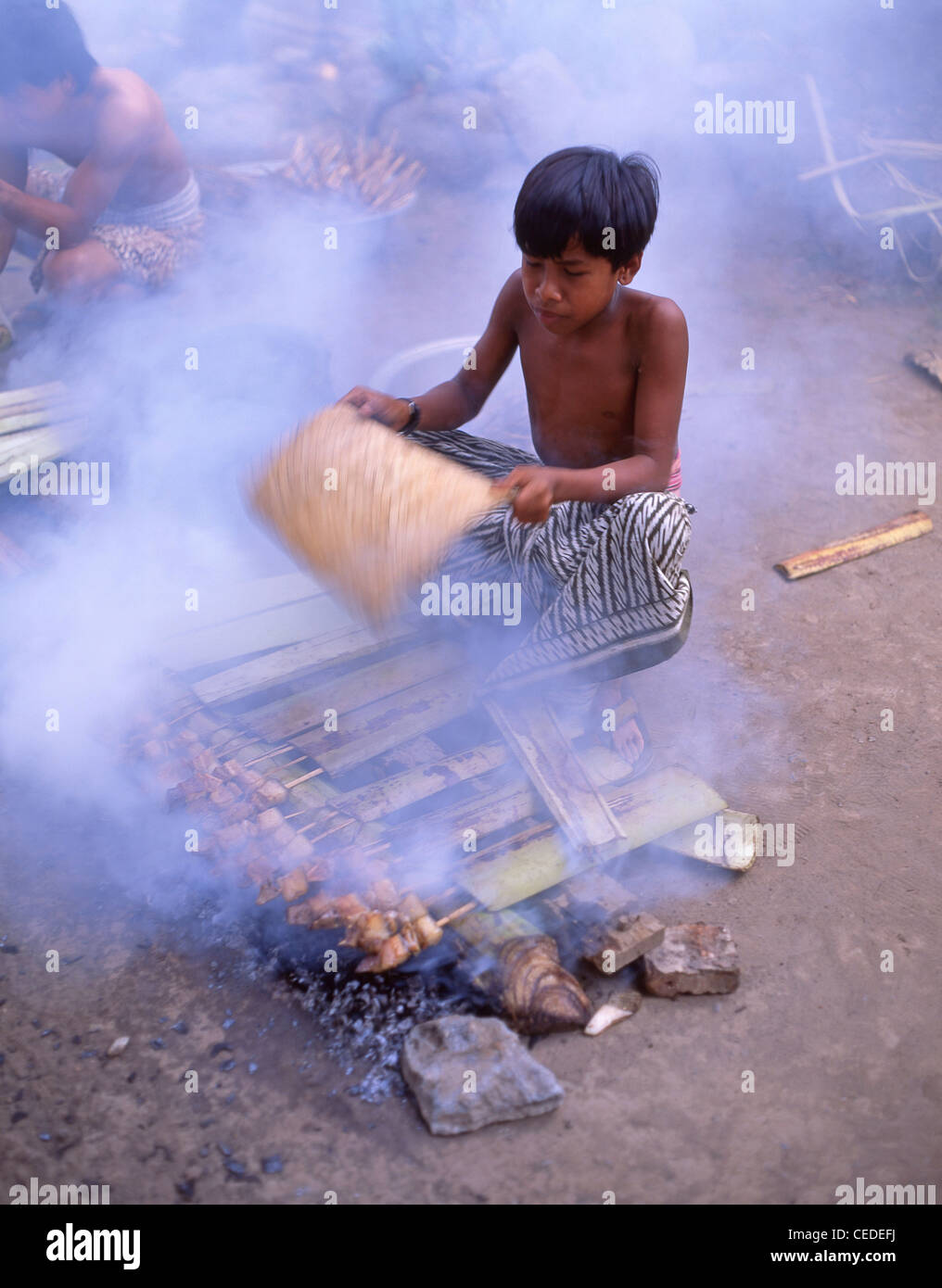Kleiner Dorfjunge, der Essen auf Feuer kocht, Tenganan, altes Dorf, Tenganan, Bali, Republik Indonesien Stockfoto