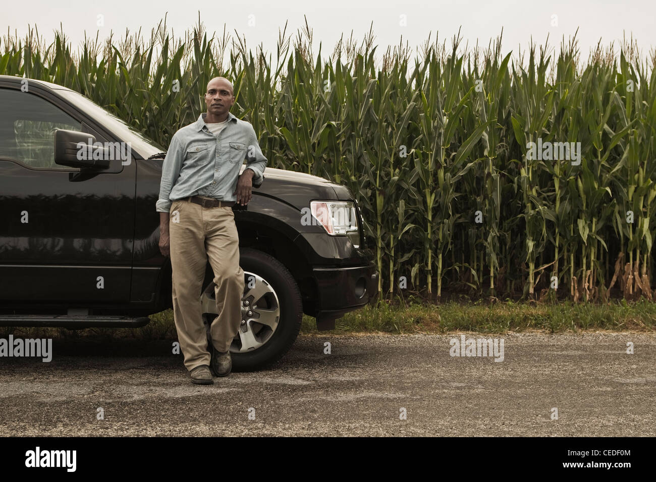 African American Farmer stützte sich auf Auto neben dem Zuschneiden Stockfoto