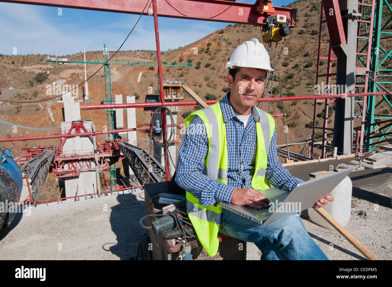Hispanische Bauarbeiter mit Laptop auf Baustelle Stockfoto
