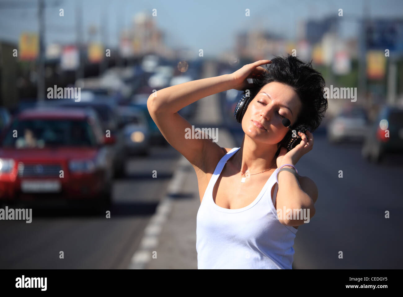 Mädchen hört Musik im Kopfhörer auf Autobahn Mitte Stockfoto