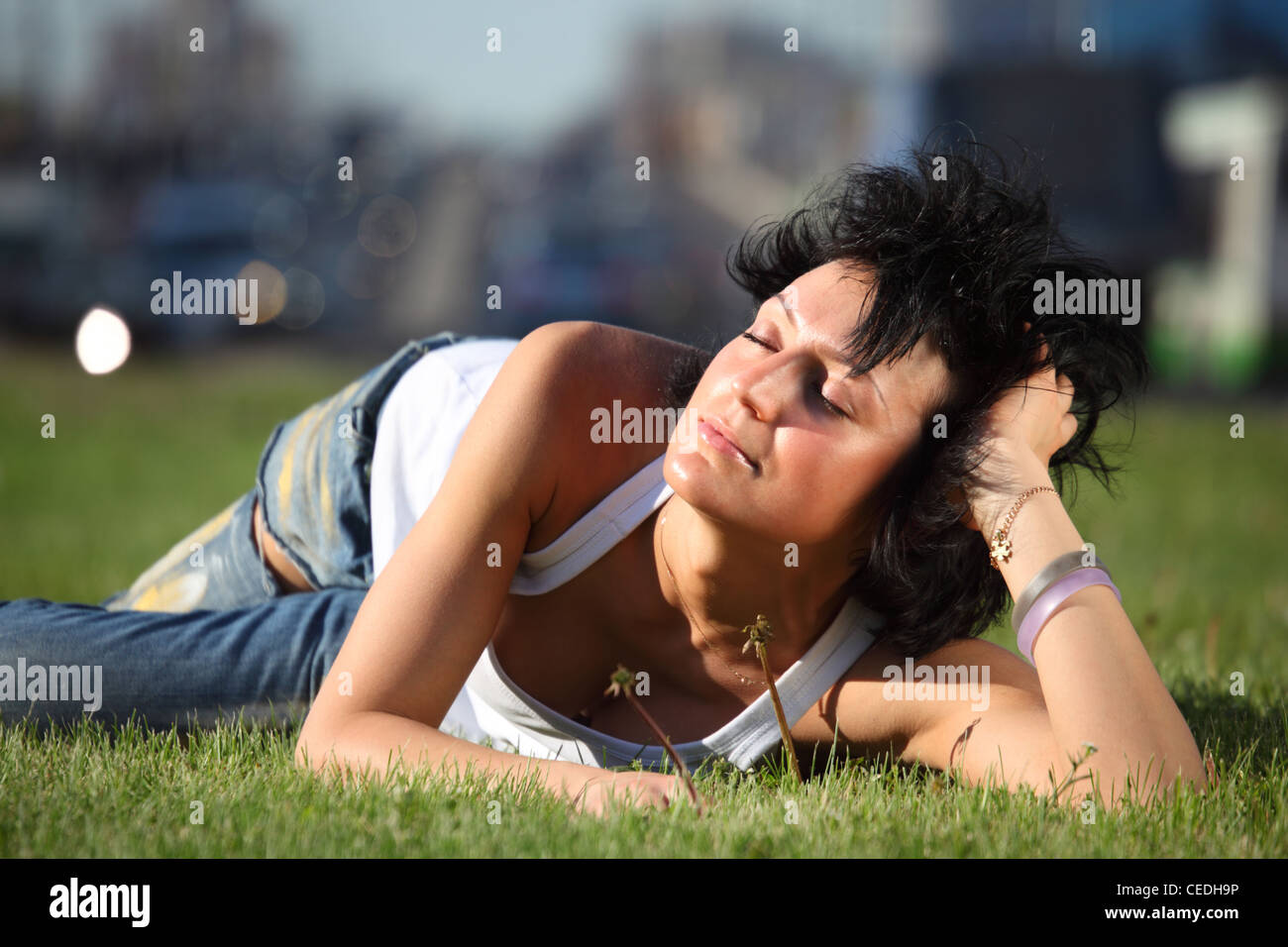 Mädchen liegt auf Rasen an Straße in Stadt Stockfoto