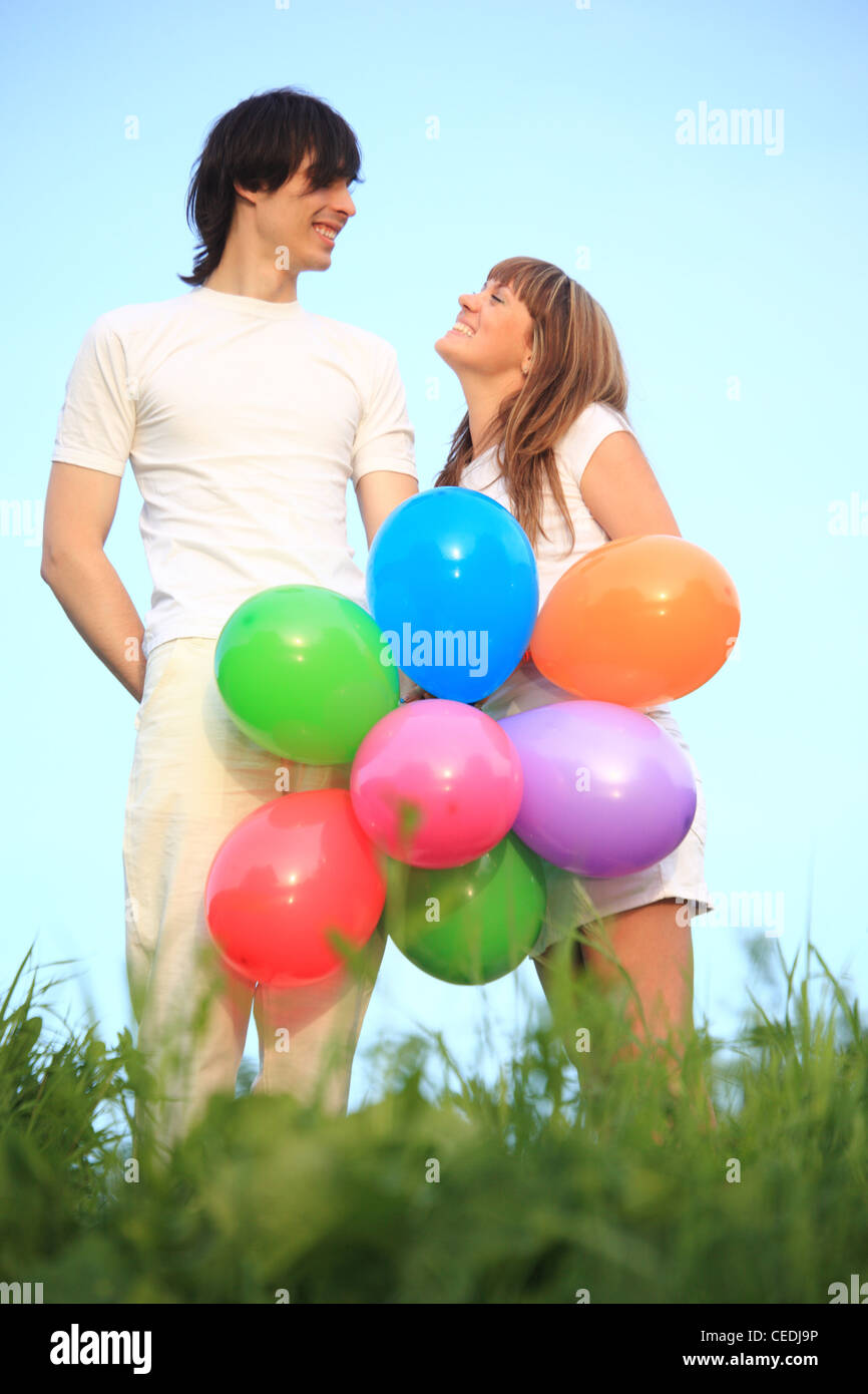 Mädchen und junge stehen auf Wiese mit bunten Luftballons Stockfoto