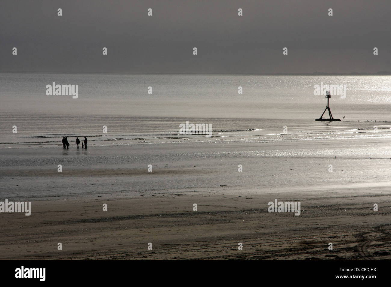 Silhouette-Bild von Menschen zu Fuß am Strand bei Ebbe in helle Morgensonne. Stockfoto