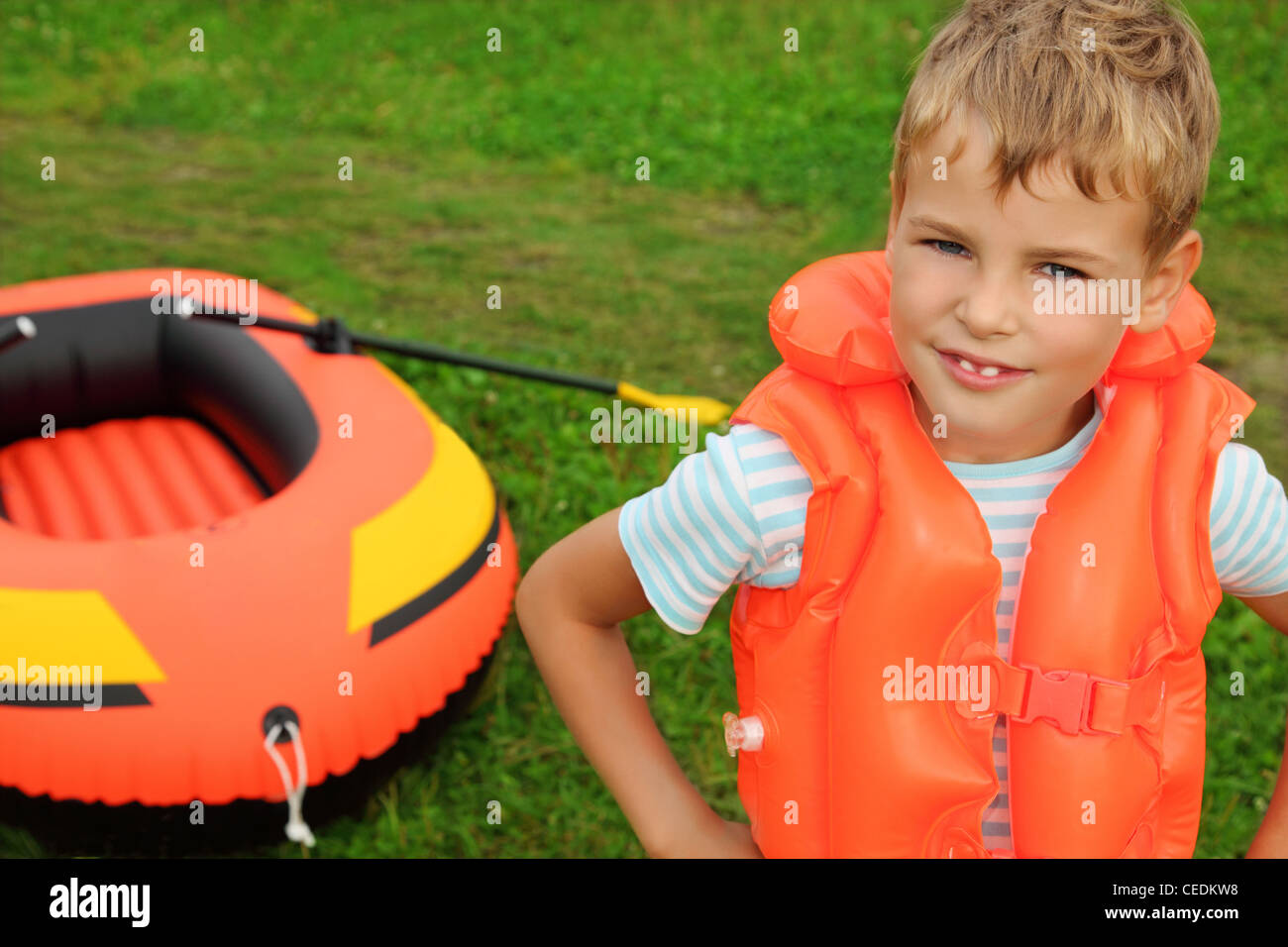 junge und aufblasbare Boot auf Rasen Stockfoto