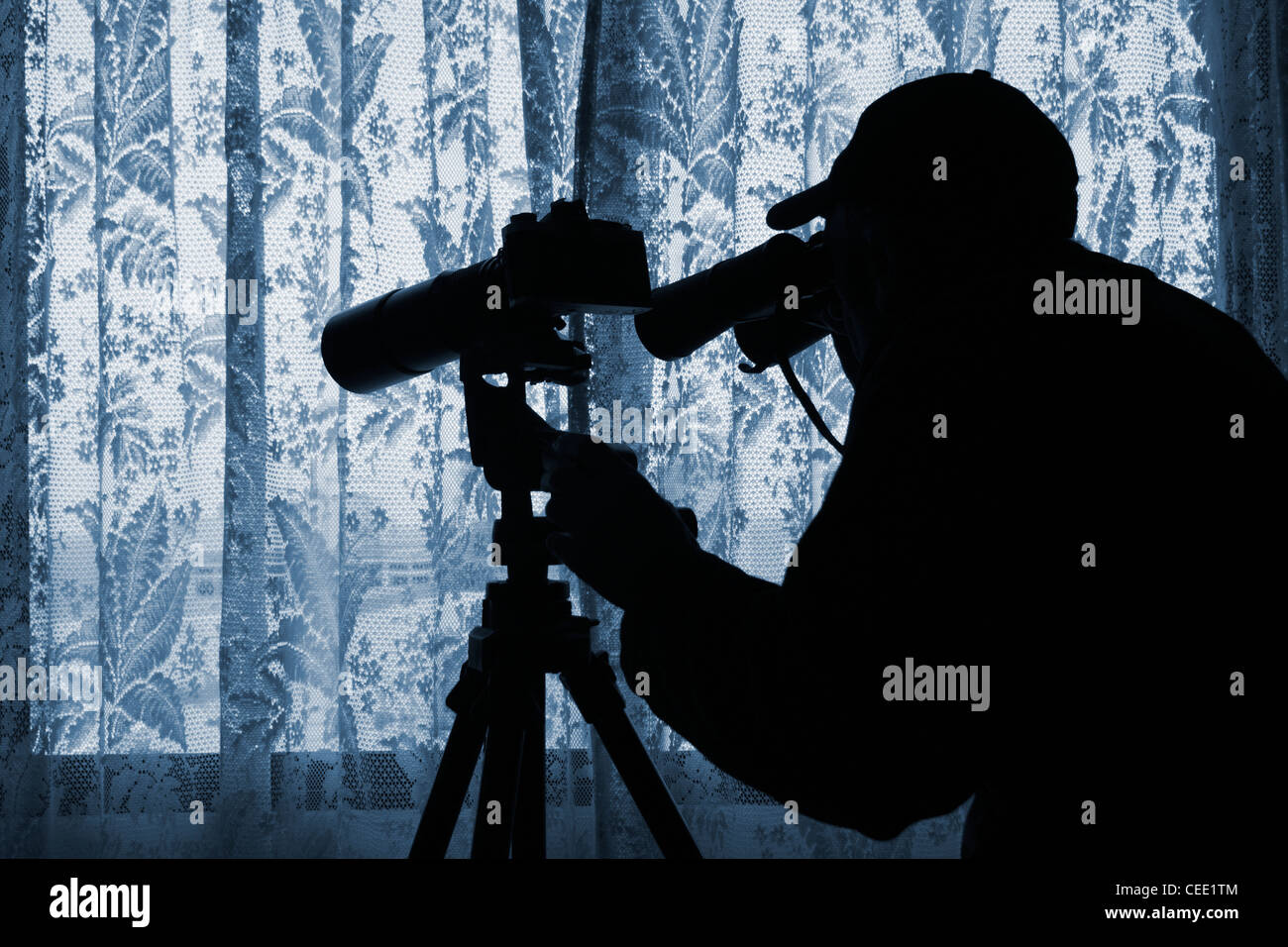 Mann mit Fernglas und Kamera mit Teleobjektiv auf Stativ Blick durch Gardinen. Foto von Model posierte. Stockfoto
