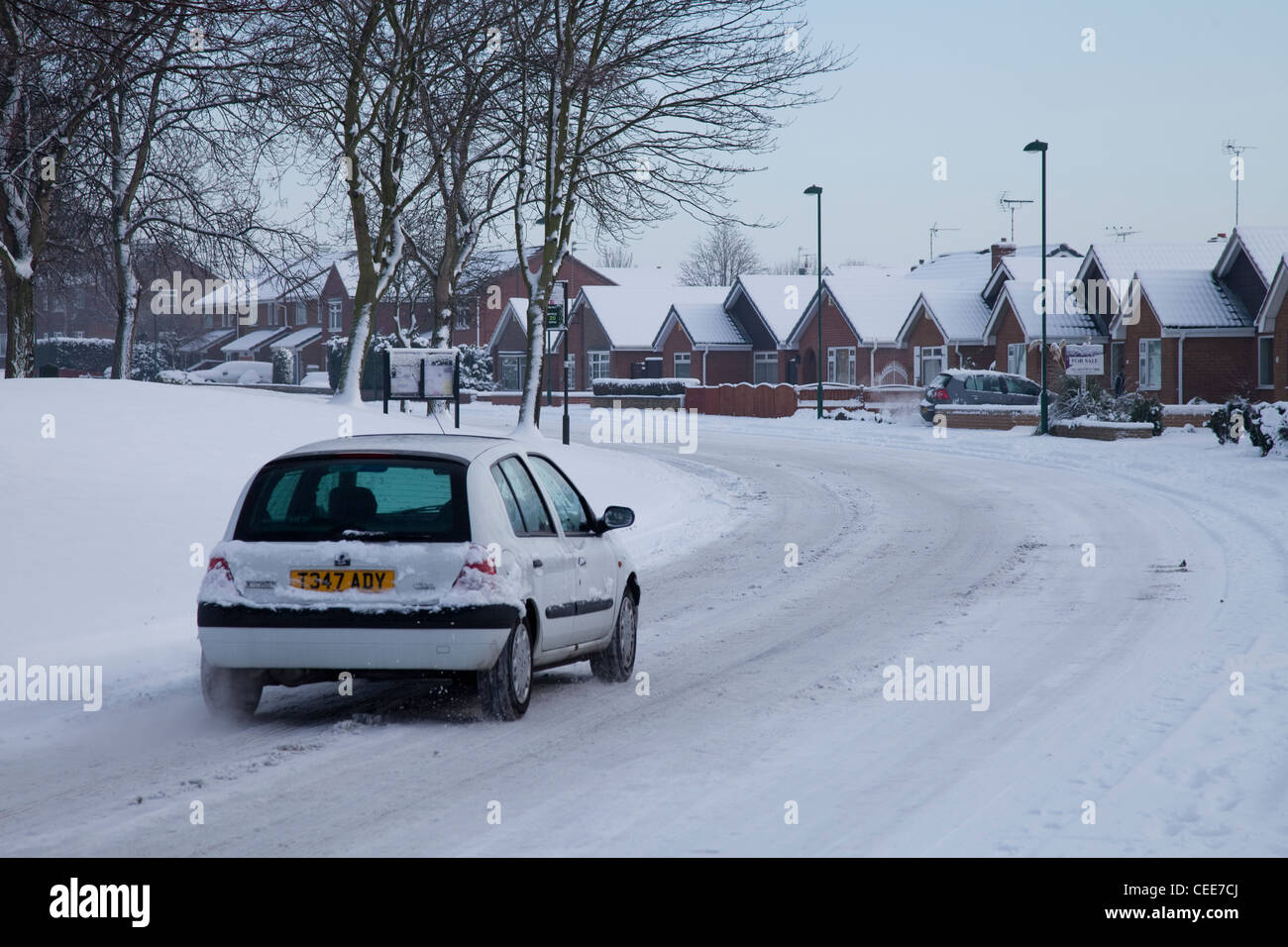 Ein weißes Auto fahren unter gefährlichen Bedingungen im Schnee in einem Wohngebiet Nottingham England UK Stockfoto