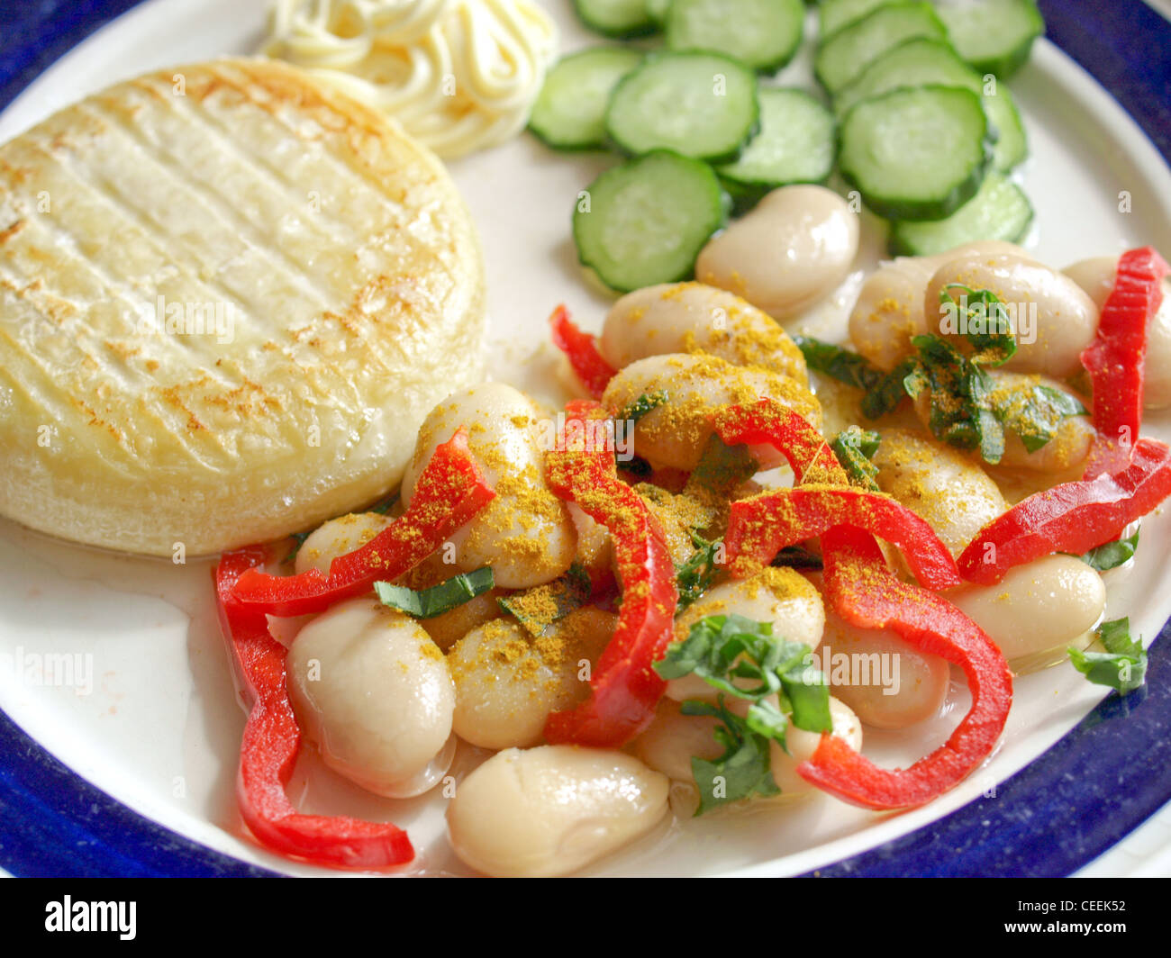 Vegetarisches Hauptgericht einschließlich Käse, Mayonnaise, Curry, Bohnen, Paprika und Gurken Stockfoto