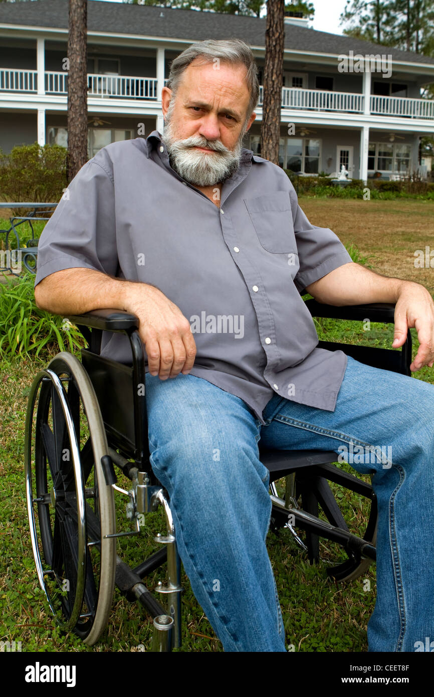 Behinderte Menschen verkrüppelt Mann sitzt im Rollstuhl vor seinem Haus auf der Wiese. Stockfoto