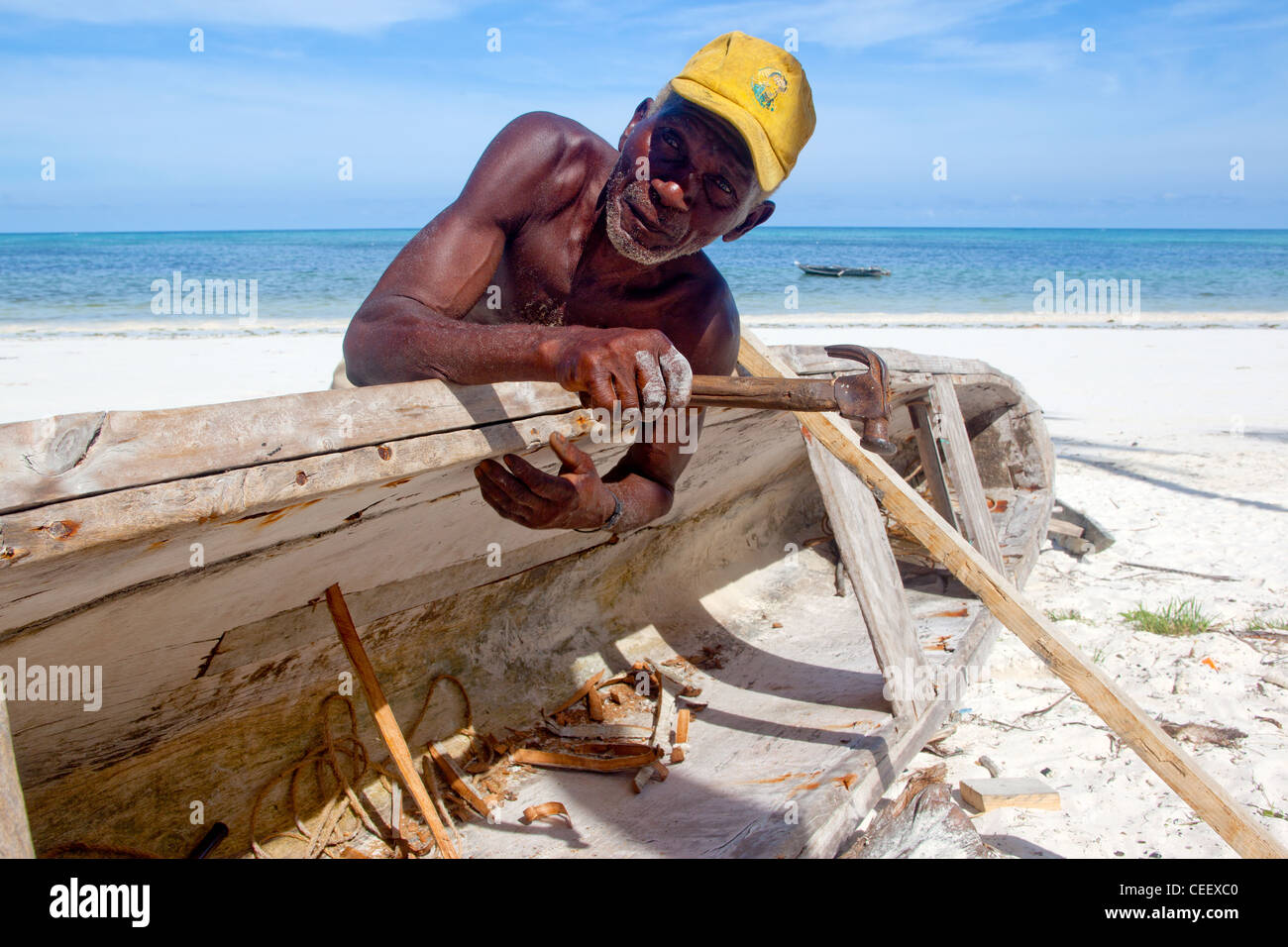 Zanzibari Greis Reparatur einer hölzernen Dhau am Strand von Bwejuu, Sansibar, Tansania Stockfoto