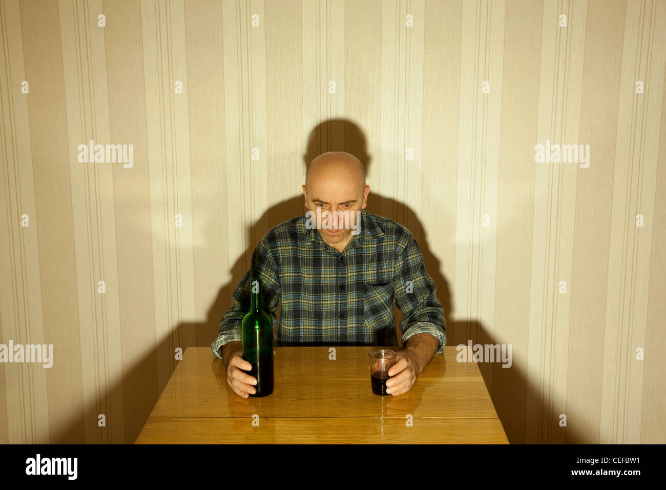 einsame betrunkene Männer sitzen in der Tabelle mit Flasche Stockfoto