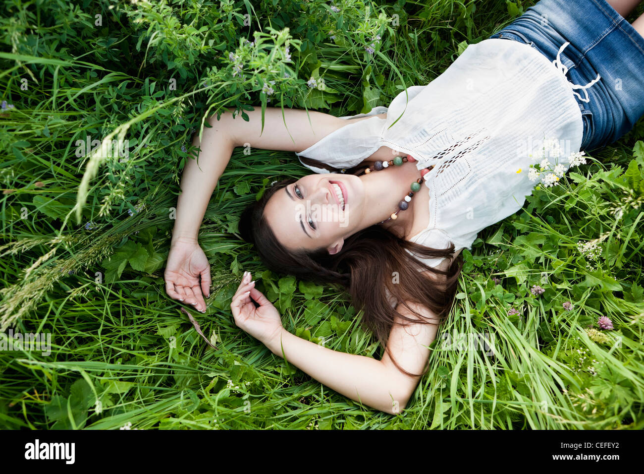 Lächelnde Frau Verlegung in hohe Gräser Stockfoto