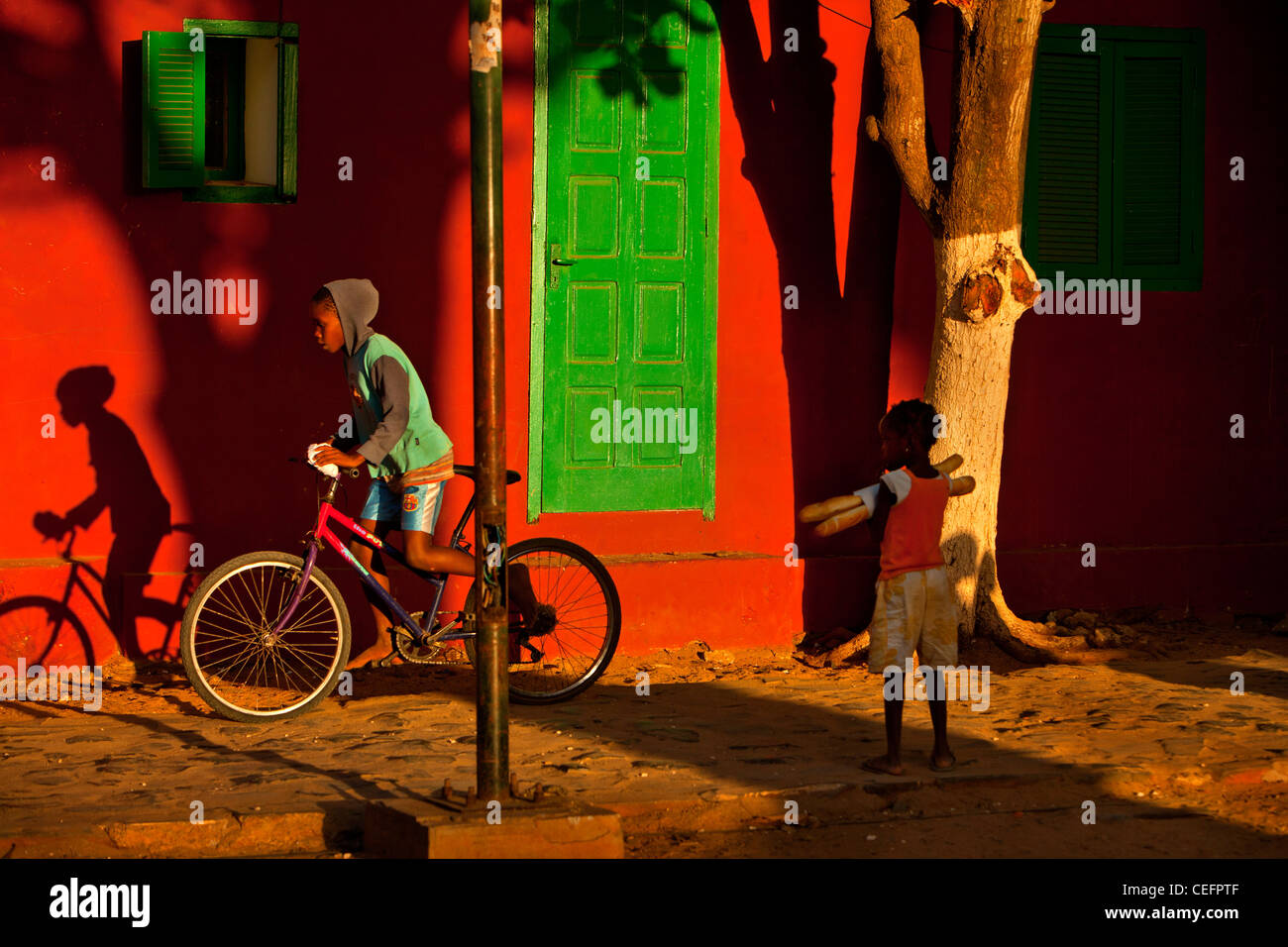 Gorée Insel. Junge mit Baguettes Uhren sein Bruder Radfahren. Es gibt eine starke französische Kultur in Senegal Stockfoto