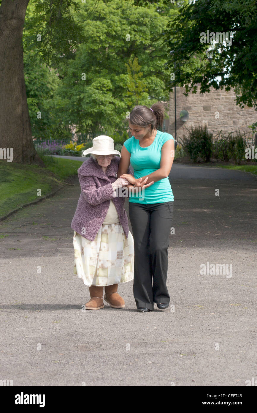 junge Frau zu Fuß mit alte Dame im park Stockfoto