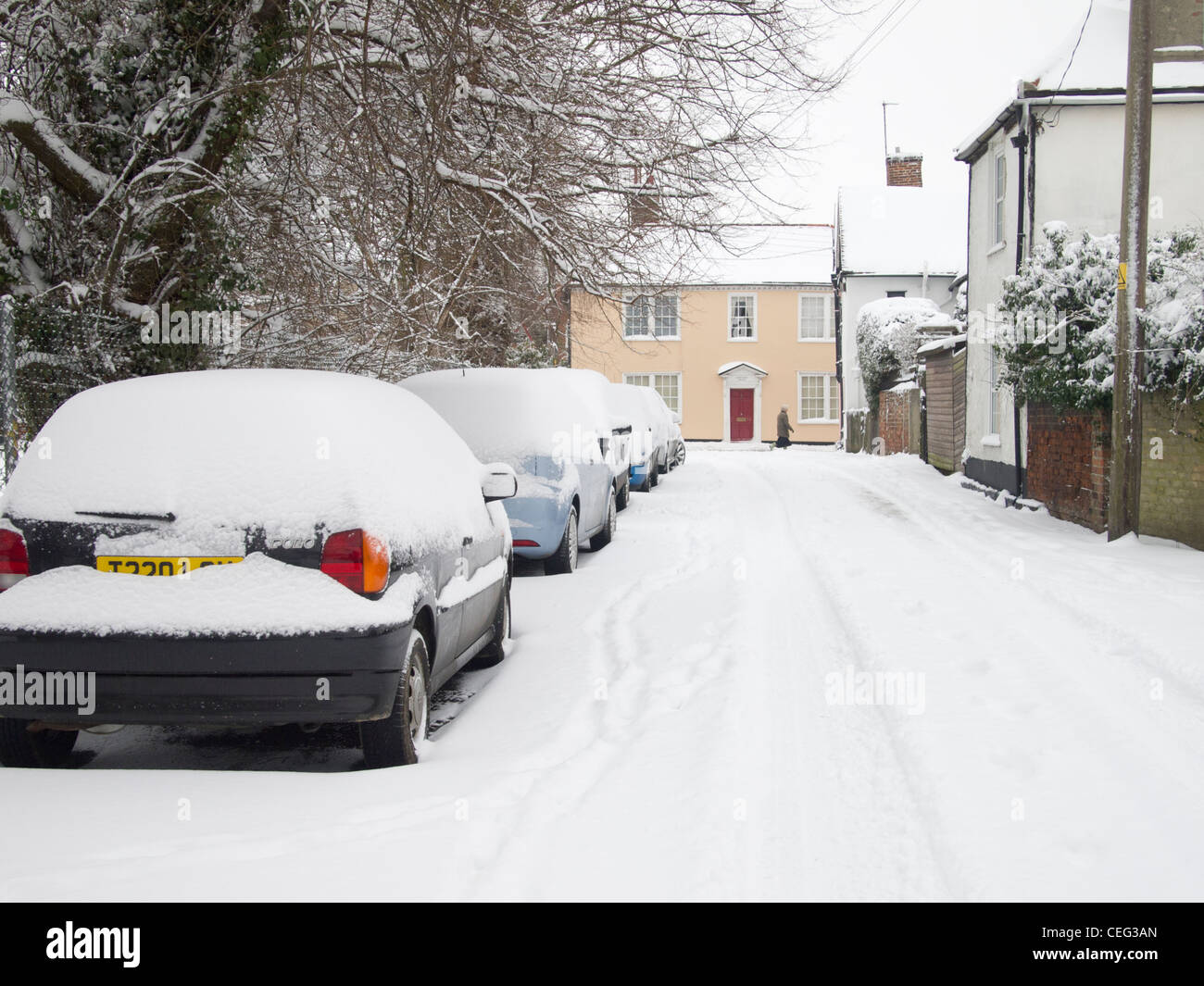Eine Reihe von parkenden Autos in Schnee bedeckt, auf der Seite einer Straße in England im Winter. Stockfoto