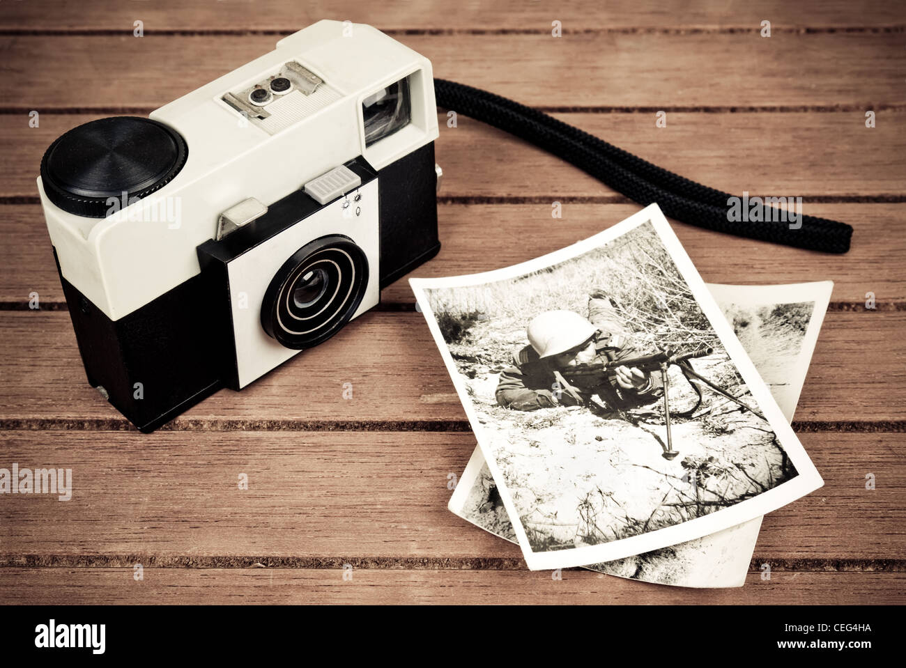 Alte Kamera mit ein paar alten Fotos eines jungen Soldaten auf einem Tisch. Das Bild hat einen Vintage-Effekt. Stockfoto