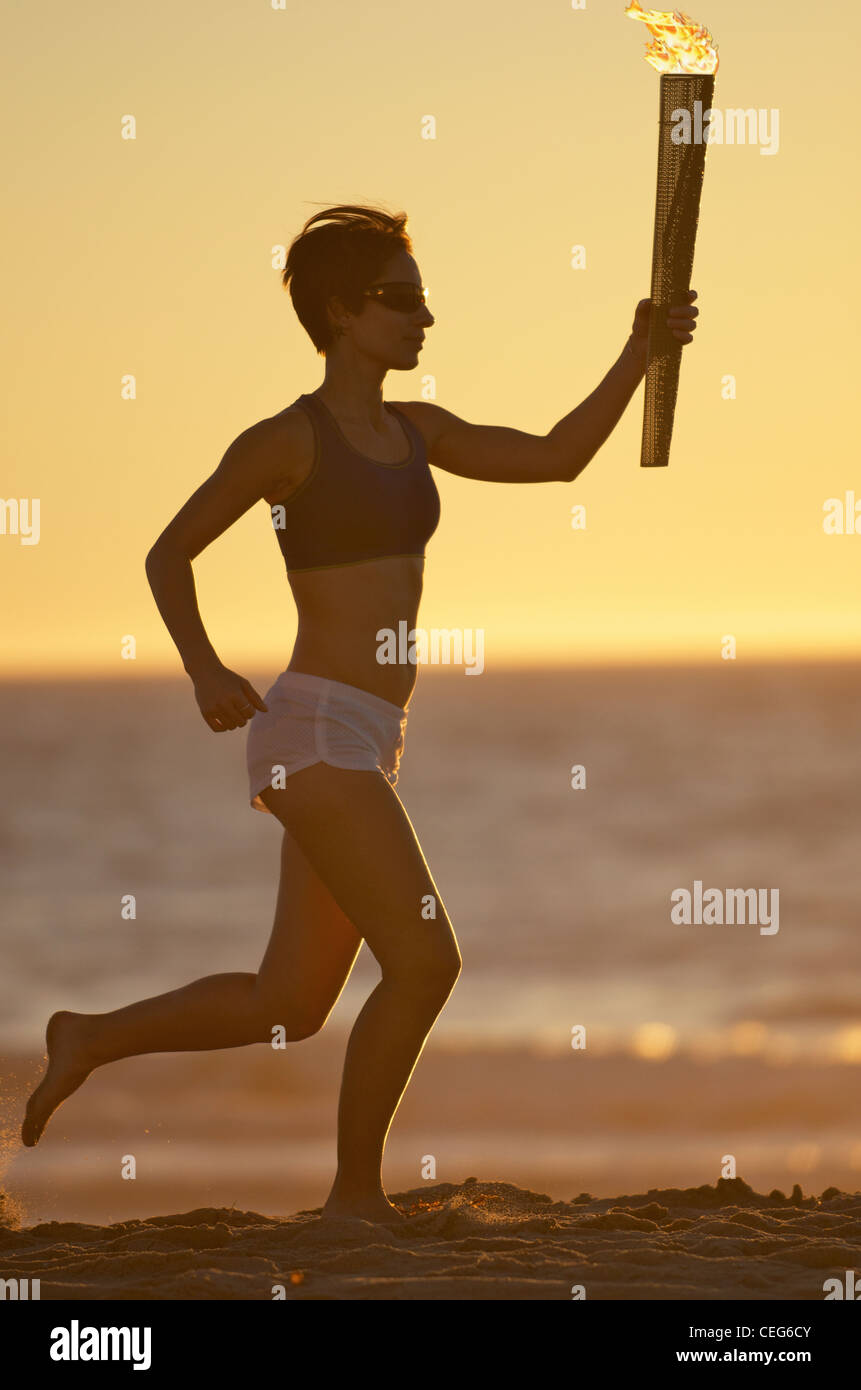 Eine Frau am Strand mit einer simulierten Olympics Relais Fackel ausgeführt. Stockfoto