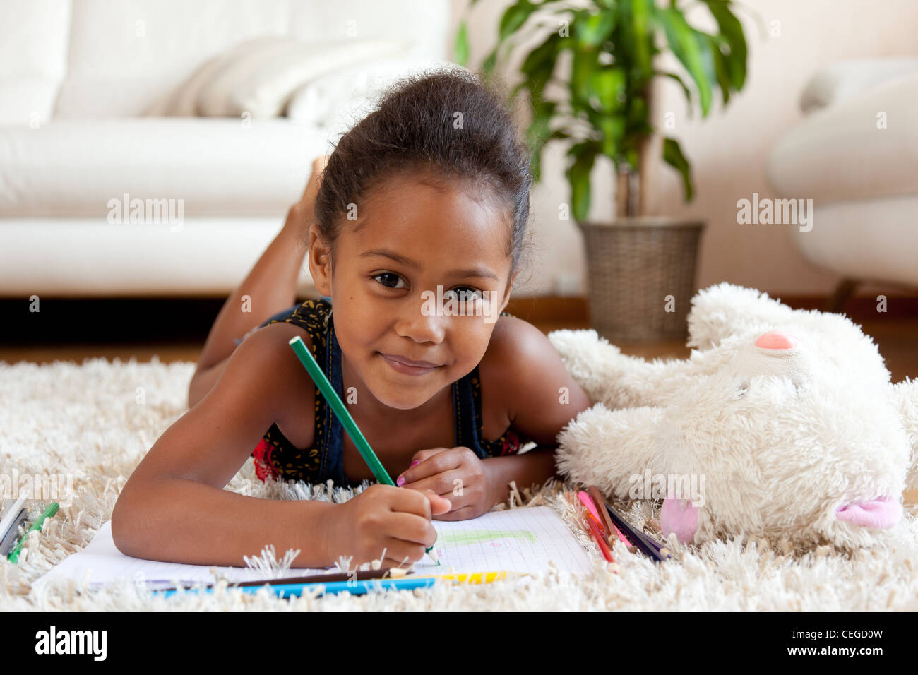 Kleine afrikanische Asiatin zeichnen, auf dem Boden liegend Stockfoto