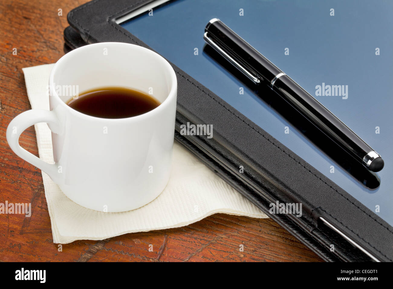 Tasse Espresso, Stylus Stift und Tablett-Computer im schwarzen Leder-Etui auf einem Grunge-Holz Stockfoto