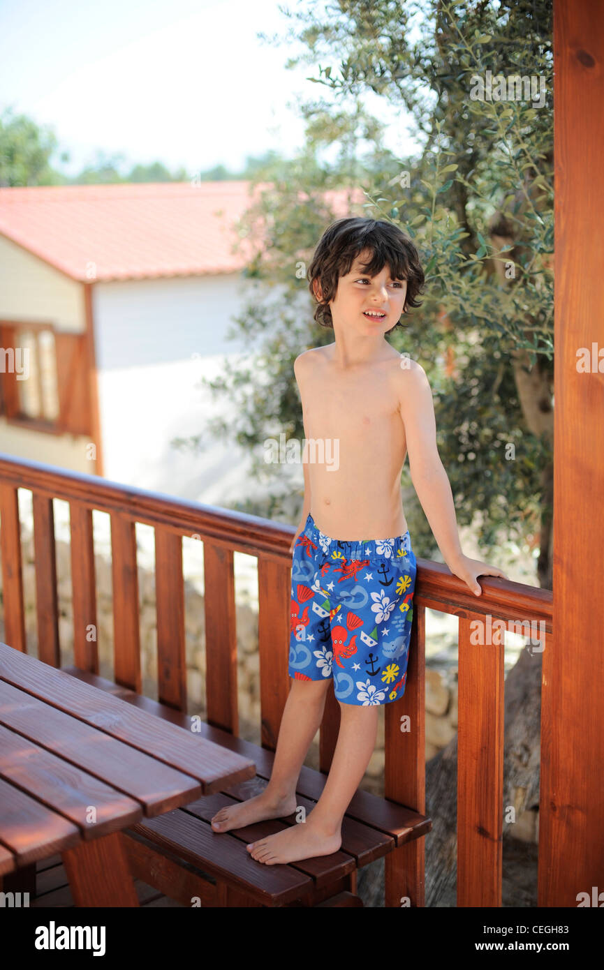 Junge stand auf Bank in Holzhütte im Sommer Stockfoto