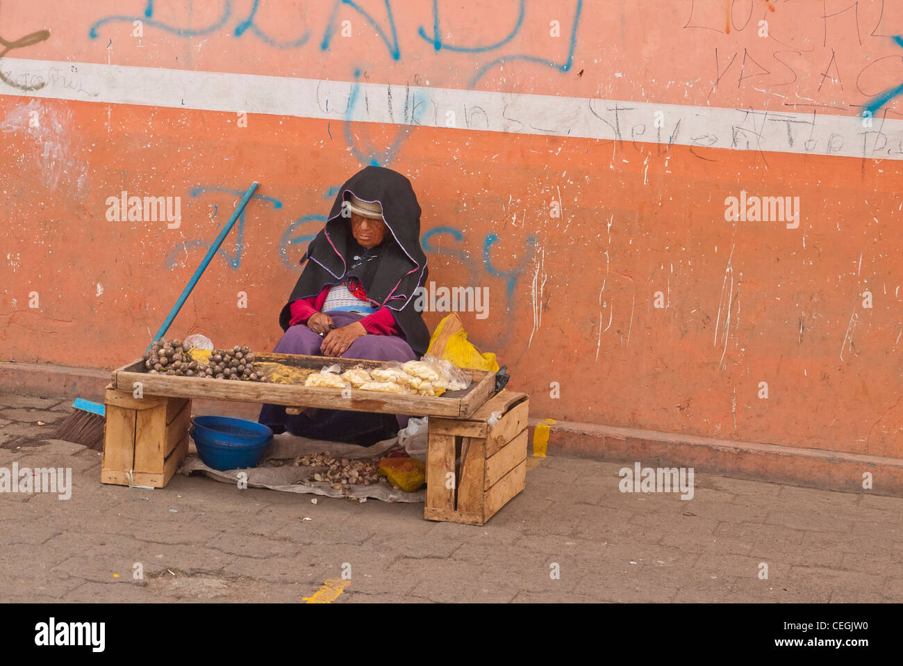 Eine 70-80 Jahre alten ecuadorianischen Indianerin sitzt und döst hinter ihrem kleinen Stall auf dem Markt in Latacunga, Ecuador. Stockfoto